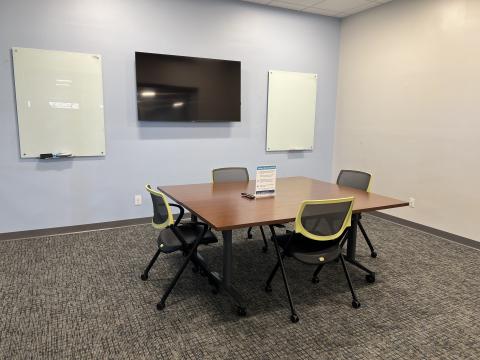 The image is a picture of Meeting Room 1, with the tables arranged in a rectangle, surrounded by 4 chairs.