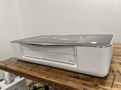 Image of the Glowforge Pro on a table. The filter is visible in the background.